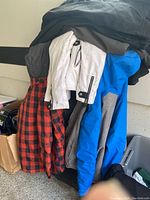 Stack of winter jackets and pants in various colors and styles