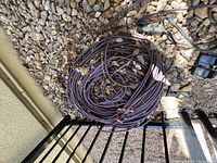 Purple Terex cable coiled on rocky ground with multiple connectors visible on one end.