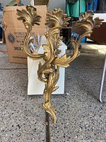 Single gold leaf finish wall candle sconce with three ornate curved arms for candles.