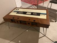 Front-angle view of coffee table showcasing wooden cassette-shaped body and hairpin metal legs