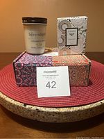 Photo of Serendipity glass jar candle and Fleur de Bois boxed candle on patterned box