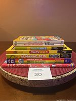 Stack of 7 children's books including Family Circus comics, National Geographic Kids books, Garfield themed books, and a drawing activity book.