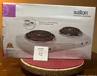 Front view of the Salton portable cooktop box showing the image of the cooktop with two coil burners, brand name, and product details.