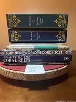 Stack of 8 hardcover books showing spines and some front covers, titles visible include trivia, world records, and nature topics.