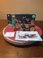 LEGO Wintertime Carriage Ride set assembled with horse and three minifigures displayed in front of the original box and instruction manual on a round table.