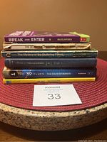 Seven children's mystery books stacked on a round table mat, showing spine titles.