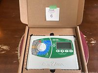 Open view of Rain Bird irrigation controller model ESP-Me inside its box showing dial, display and buttons