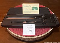 Carving fork and knife in black case with instruction card and MaxSold lot number on table
