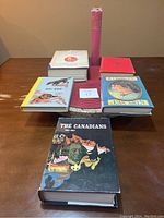 Top view of six vintage hardcover books arranged on a table with various colors and titles visible.
