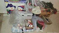 Overview of assorted Christmas decorations including large snowmen boxes, tinsel garland, and storage bags with ornaments.