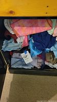 Fabric pieces stacked in a drawer showing pink tie-dye, blue and pastel fabrics