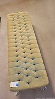 Full view of greenish tufted fabric settee bench showing the entire length and tuft pattern.