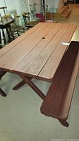 Image of the wood picnic table with bench seats showing the table top with a central hole and attached benches with darker wood.