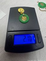 Jade pendant on digital scale showing a combined weight of 2.10 grams.