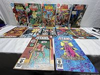 Set of 12 vintage The New Teen Titans comic books laid out, showing colorful covers and condition.