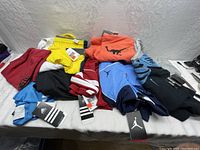 Lot of folded new Nike and Jordan clothing items including shorts, pants, and tops in multiple colors with tags attached.