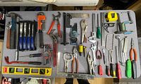 Wide view of most tools laid out on a table including hammers, wrenches, clamps, screwdrivers, pliers, chisels, levels, and measuring tools.