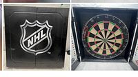 Open doors revealing traditional bristle dartboard inside black cabinet with NHL emblem on front.