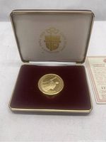 Gold-tone medal displayed inside a white hinged case lined with burgundy velvet and cream satin with gold embossed logo for Pope John Paul II's 1984 Canada visit
