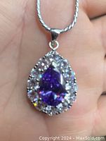 Close-up of the teardrop pendant showing purple and white cubic zirconia stones set in sterling silver.