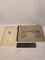 Photo of the front cover and an additional booklet included shown lying flat on a white background.