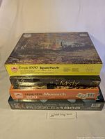 Stack of four sealed vintage jigsaw puzzles showing various puzzle brand labels and box art