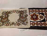 Two stacks of placemats laid flat, one stack shows a bird and flower design, the other shows a floral pattern with a black border.