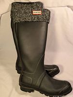 Pair of black Hunter rubber boots with knitted sock liners folded over the top showing the Hunter logo.