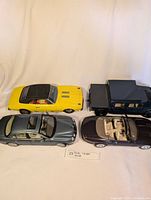 Top view of all four vehicles showing the yellow muscle car, light blue sedan, dark convertible, and dark blue pickup RC car.