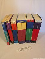 Side view of Harry Potter book spines showing nearly complete collection in two row stacks, showcasing various colors and different editions including hardcover and paperback.