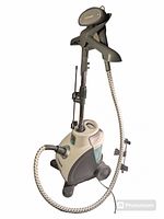 Full view of the Conair fabric steamer showing the main unit with wheels, water reservoir, adjustable pole, and steam hose attached to the nozzle.