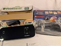 Photo showing FoodSaver vacuum sealer and Starfrit mandolin with their boxes.