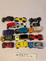 Top view of 12 assorted vintage diecast Hot Wheels cars displayed on a white surface.