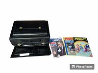 Photo of the closed hard body black briefcase and three vintage Private Eye magazines laid out beside it.