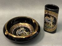 Black ceramic ashtray and matching toothpick holder with 24k gold Greek key pattern and classical Greek figures in multicolor on a glossy finish.