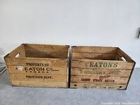 Side view of two wooden crates with Eaton's branding and text, showing wood grain and handle openings.