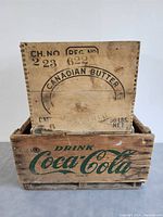 Photo of a wooden Coca-Cola crate with a wooden Canadian Butter crate inside