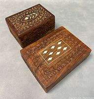 Two vintage hand carved wooden jewelry/trinket boxes shown together on a neutral surface, highlighting size, shape, and top carved designs with inlays.