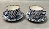 Two vintage Lomonosov teacups and saucers set showing blue and gold lattice pattern and gold trim