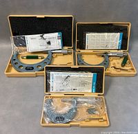 Three Mitutoyo micrometers in original yellow plastic cases with foam inserts, including manuals and calibration certificates.