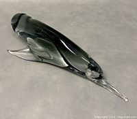 Smokey gray and clear glass swordfish paperweight on neutral surface showing side profile and clear fin detail.