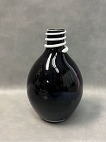 Front view of black glass vase showing bulbous shape and white coil detail on neck against a grey background.