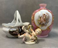 Front view showing the porcelain basket, cherub figurine lying on its side, and vase with cherub painting.