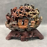 Front view of the intricately carved vintage soapstone sculpture showing a house, trees, and nature scene in earthy colors.