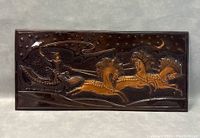 Front view of rectangular copper wall plaque showing embossed design of charioteer driving a chariot drawn by three horses beneath a starry night sky with crescent moon.