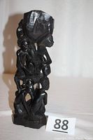 Full front view of the carved ebony sculpture showing the six figures and large top block.