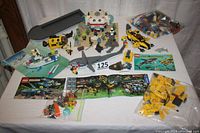 Full overview of all Lego sets and components included in the lot on a white table showing underwater vehicles, minifigures, Lego instruction manuals, and loose bricks.