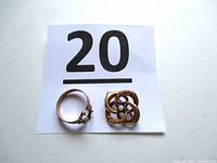 Photo showing the side and profile of the gold ring and brooch with small stone side by side.