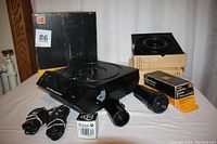 Full view showing the Kodak Carousel 4400 projector, lenses, remote controls, lamp box, and two empty slide trays on table.