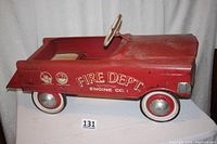 Side profile showing red metal fire engine pedal car with Fire Dept Engine Co. 1 graphics on side and whitewall tires.